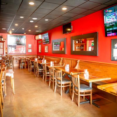 Casual restaurant with red walls, wooden tables and chairs, and TV.