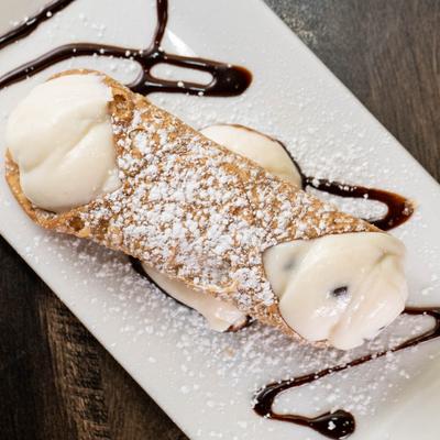 Cannoli with powdered sugar and chocolate drizzle.