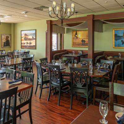 Restaurant interior with wooden tables and desert-themed wall art.