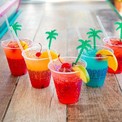 Multi colored nonalcoholic drinks served in cups with fruit garnish.