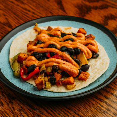 Open-faced taco with sweet potatoes, beans, and chili aioli.