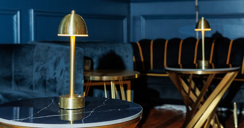 Stylish and elegant lounge area with dark velvet sofas and round tables with black marble tops