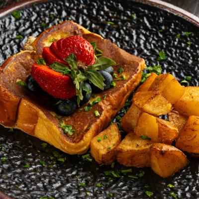 French toast with berries on top and potatoes on the side