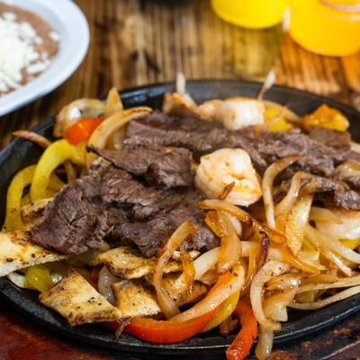 Steak, shrimp, and chicken Fajitas, with grilled onions and bell peppers.