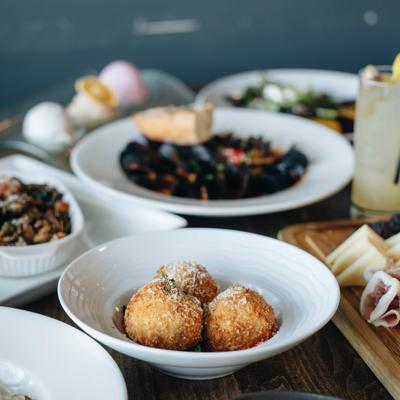 Arancini served on the table beside other dishes and a cocktail.