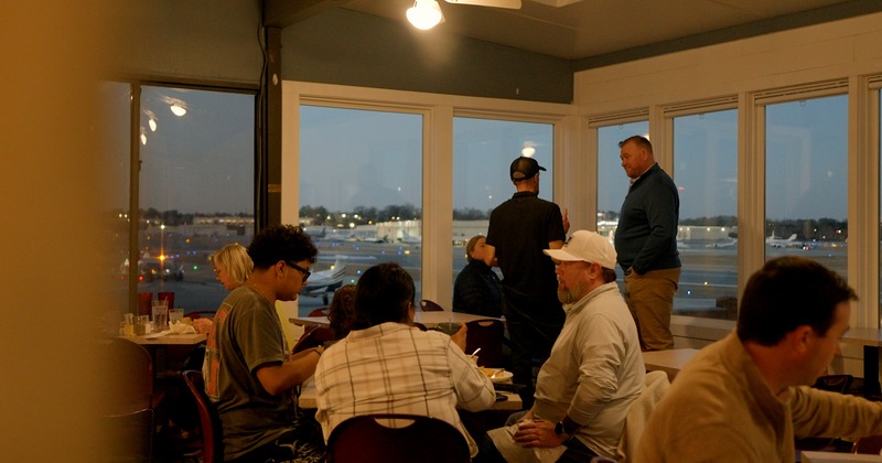 Patrons dining and looking out at parked airplanes through large windows