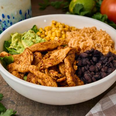 Chicken rice bowl with black beans, corn, guacamole, and greens.