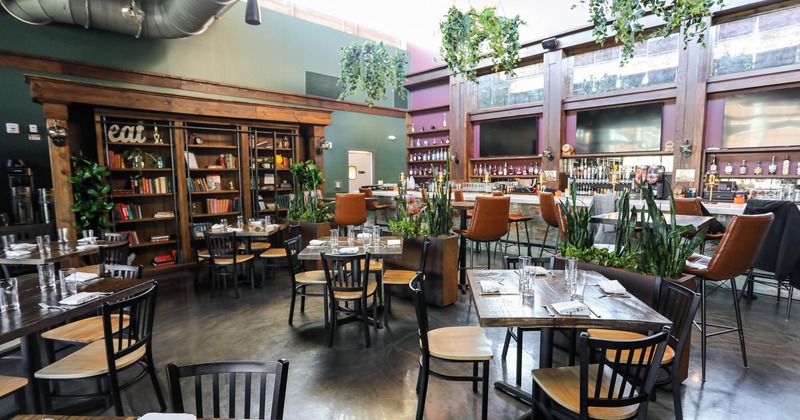 Interior, tables and chairs, plants, bookshelf and a bar