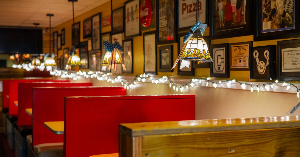 Interior of a diner with red booths, stained-glass lamps, and framed memorabilia on the walls