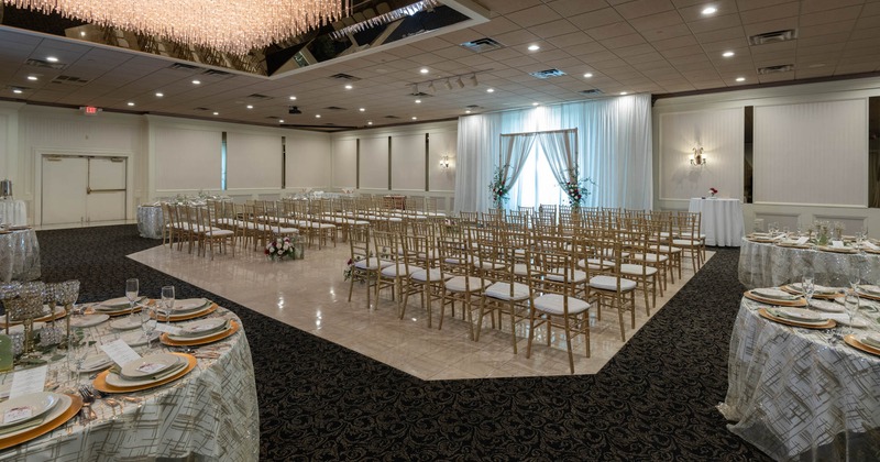 Interior, wedding venue, ceremonial arch, lined up chairs i seven rows, round tables