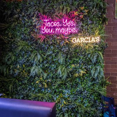 Green leafy backdrop with neon signs.