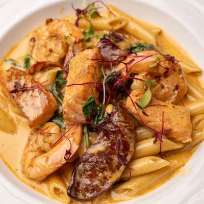 Penne pasta with shrimp, salmon and microgreens, close-up.