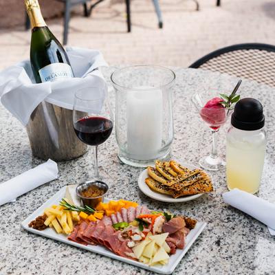 An outdoor table with a charcuterie platter served with wine and berry sorbet.