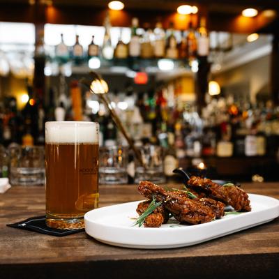 Crispy chicken wings and a glass of beer served on a bar counter.