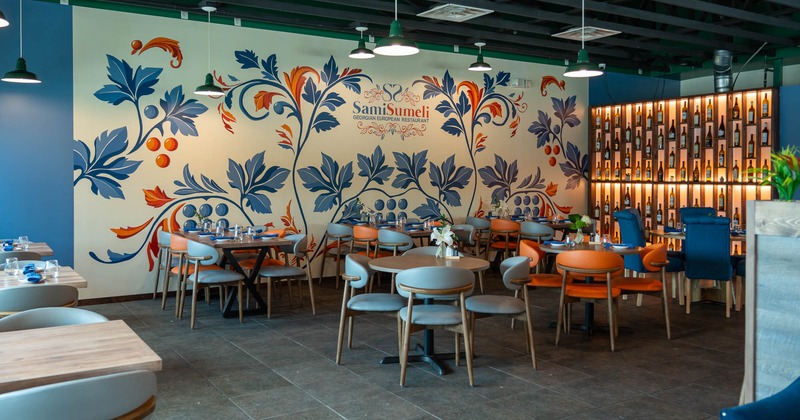 Interior, dining area, tables ready for guests, large over the wall mural with restaurant's logo