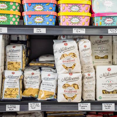 Packages of assorted pasta and gummy bears arranged on a store shelf.