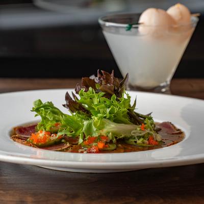 Tuna sashimi appetizer with fresh greens and roe, served with a lychee cocktail.