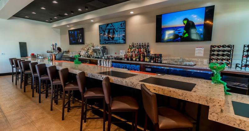 Bar and bar stools, big TV screens on the wall