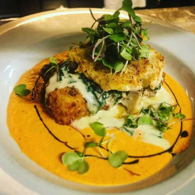 Blackened Cod, a grit cake with creamy spinach, romesco sauce, a balsamic reduction.