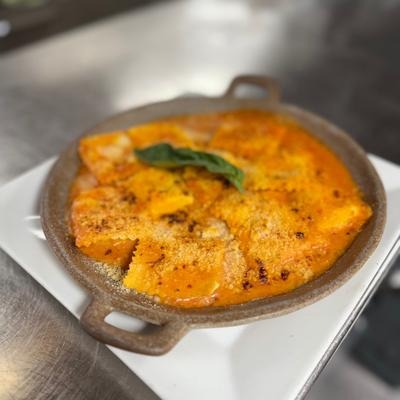 Ravioli in tomato-based sauce, served in a small cast-iron skillet.