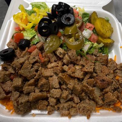 Takeout container with gyro meat served over rice with a salad on the side.