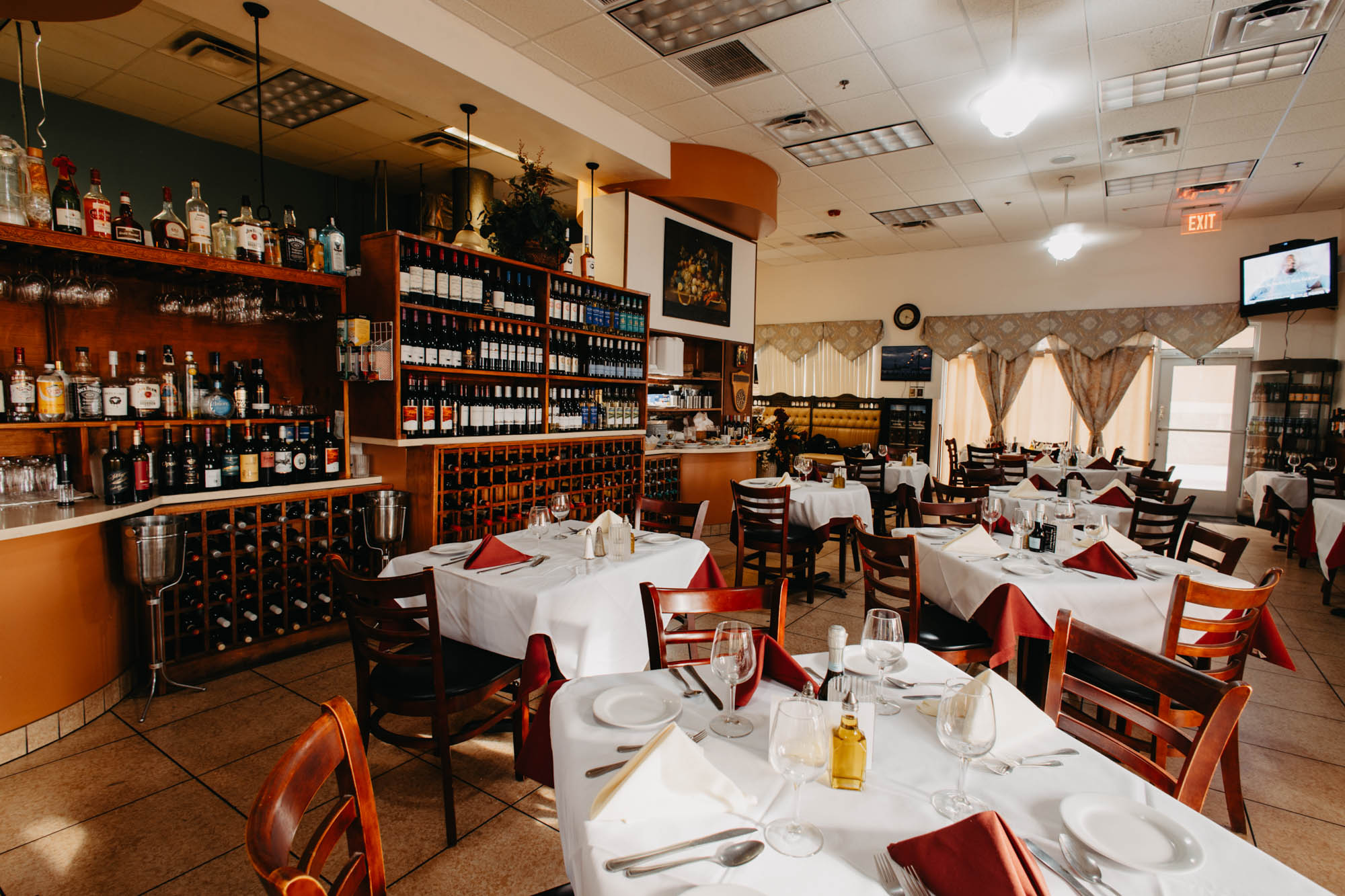 Arranged dining tables with tablecloths, set up for meal, wine racks and shelves