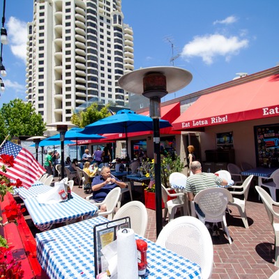 Exterior, sunny patio with parasols, guests sitting.
