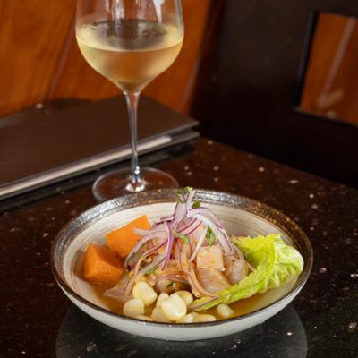 Bowl of ceviche accompanied by a glass of white wine.