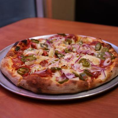 Pizza with pepperoni, jalapenos, pineapples, fresh garlic, red onions, and cilantro.