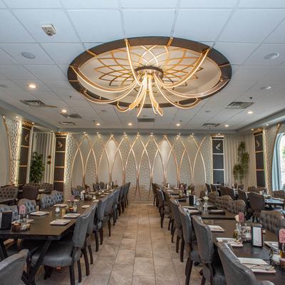 Elegant dining room with long tables set with plates and button tufted chairs.