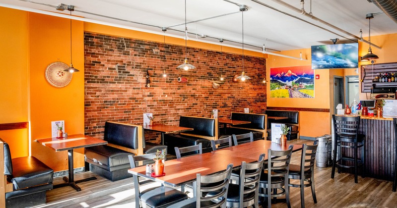 Interior with orange and brick walls, black booths, and a long table with chairs