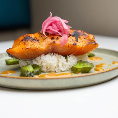 Fish filet served over rice and asparagus, topped with red onion.