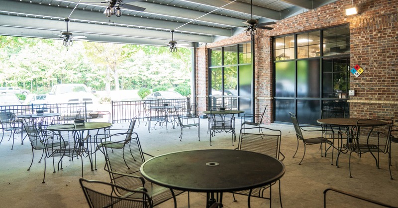 Outdoor patio with metal tables and chairs under a corrugated roof
