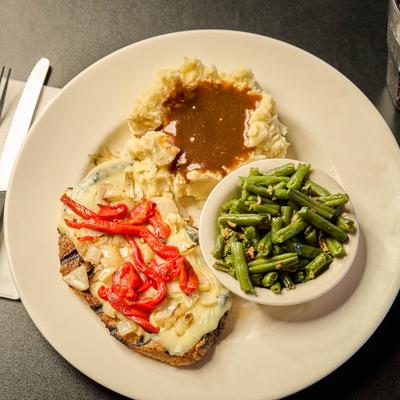 Loaded Chicken served with green beans and mashed potatoes topped with gravy.