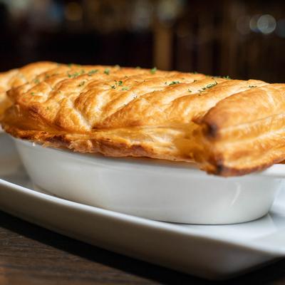 Chicken pot pie with flaky pastry crust in a white dish.