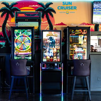 Three slot machines with chairs, inside of the restaurant.