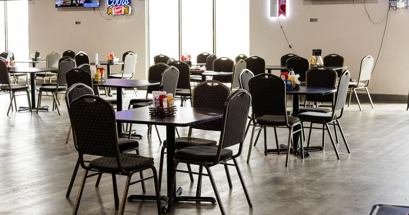 Interior view of a restaurant with tables, chairs, and neon signs.