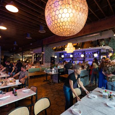 Diner area, staff preparing table, chandelier.