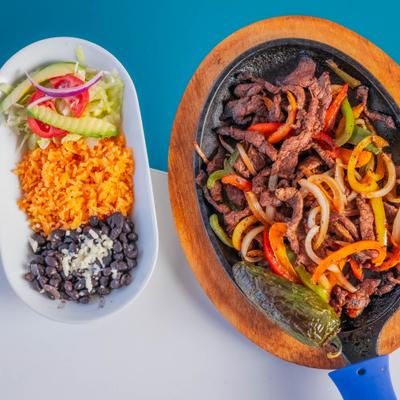 Steak fajitas accompanied by rice, black beans, and salad.
