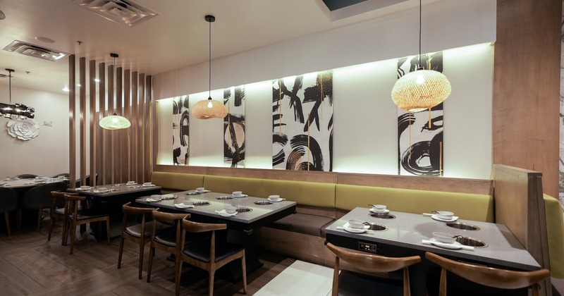Modern interior dining area with tables equipped with built-in hot pot burners