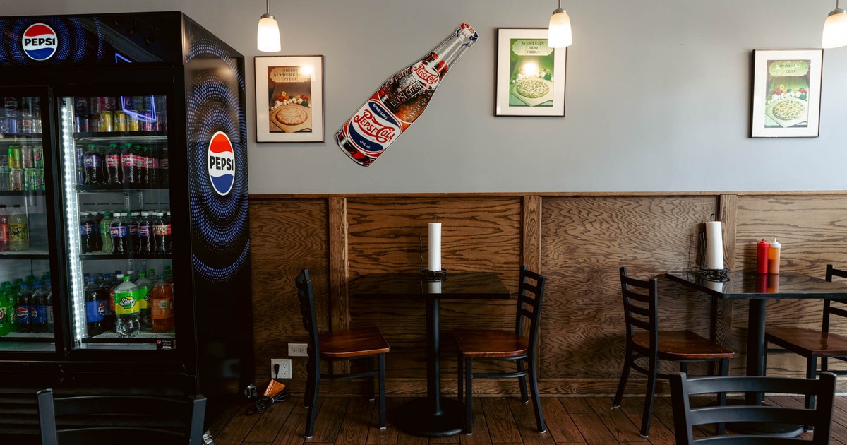 Interior, dining area, tables for two, wood coated walls, framed pictures, drinks fridge