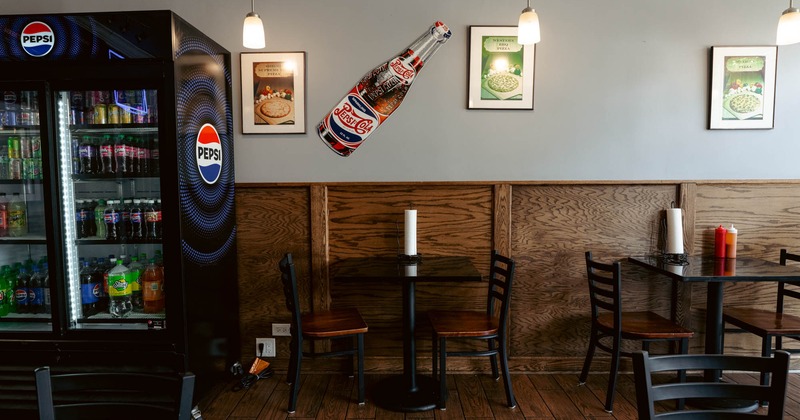 Interior, dining area, tables for two, wood coated walls, framed pictures, drinks fridge