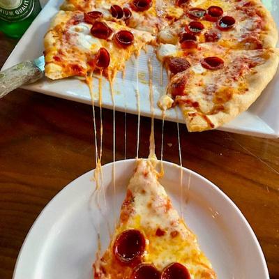 Pepperoni pizza slice with melted cheese stretching from the remaining pizza.