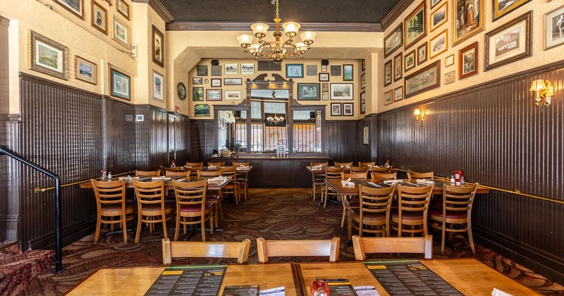 Interior with set tables, soft lighting, and walls adorned with framed photos and pictures