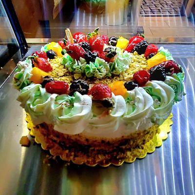 A beautifully decorated cake topped with an assortment of fresh fruits.
