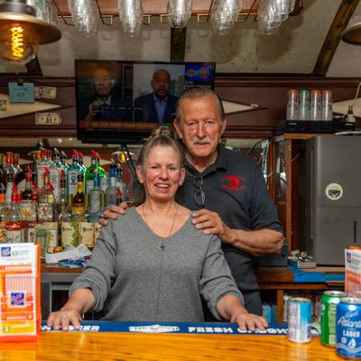 Two people standing behind a bar and smiling.