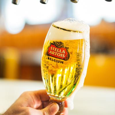 A hand holding a freshly poured light beer, dispensary