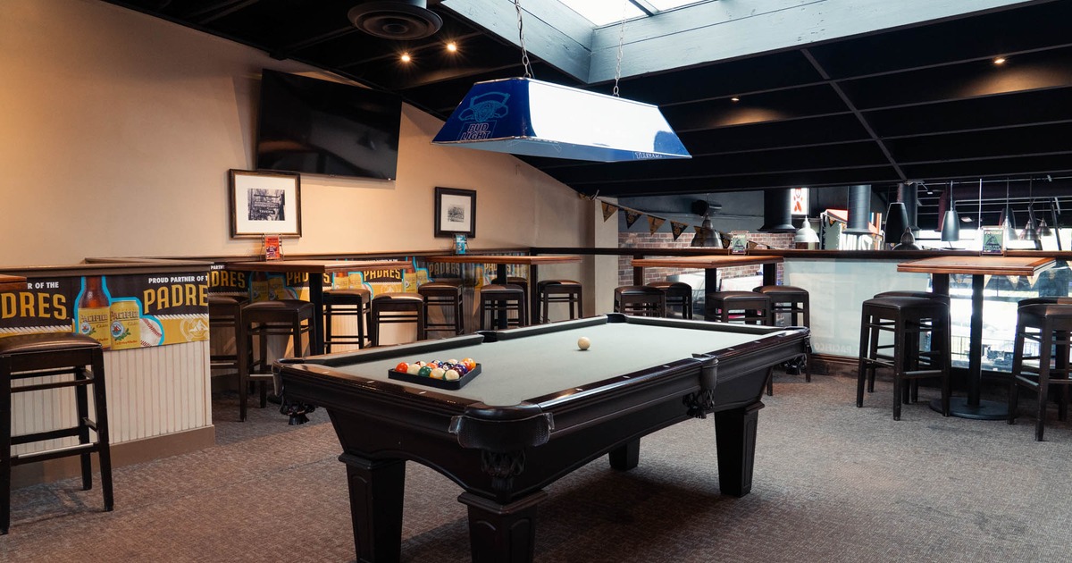Interior, a pool table set up for a game in a room with bar tables and stools