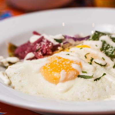 Chilaquiles Verdes with a focus on a sunny-side-up egg.