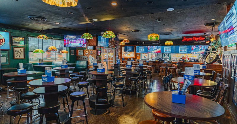 Interior, stained glass lamps, wooden tables with stools, neon sign, TVs